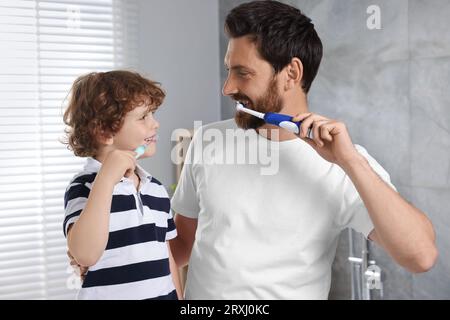 Vater und sein Sohn putzen sich im Bad die Zähne Stockfoto