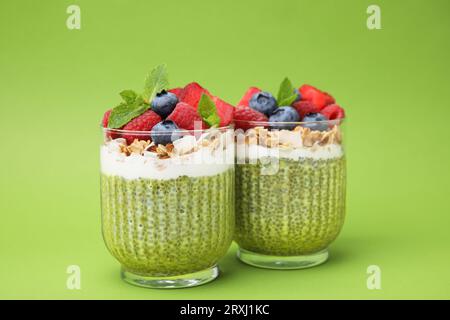 Leckerer Matcha Chia Pudding mit Haferflocken und Beeren auf grünem Hintergrund. Gesundes Frühstück Stockfoto
