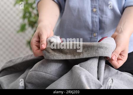 Frau zeigt Flecken vom Kaffee auf der Jacke vor verschwommenem Hintergrund, Nahaufnahme Stockfoto