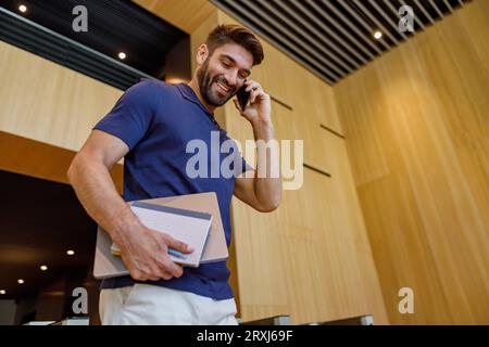 Bärtiger Geschäftsmann telefoniert mit dem Kunden, der in der Bürohalle steht Stockfoto