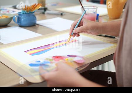 Eine Nahaufnahme der Hände einer jungen Frau, die eine Palette mit Farben hält Stockfoto