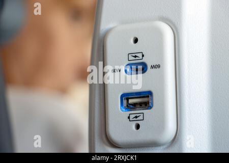 USB-Anschluss am Sitz des Flugzeugs zum Aufladen der elektronischen Geräte auf Reisen Stockfoto