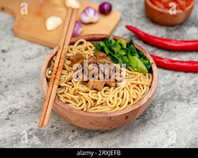 Indonesische Hähnchennudeln namens mie Ayam mit Hühnerfleisch und grünem Senf, serviert in einer Schüssel Stockfoto