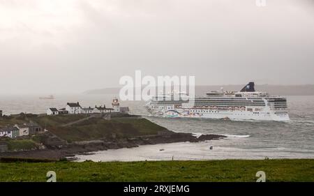 Roches Point, Cork, Irland. 25. September 2023. Mit einem ausbrechenden Nebel stampft das Kreuzfahrtschiff Norwegian Star am Roches Point Lighthouse, Co. Vorbei Cork in der Dämmerung, als sie nach Dingle, Co. Kerry segelt. David Creedon / Alamy Live News Stockfoto