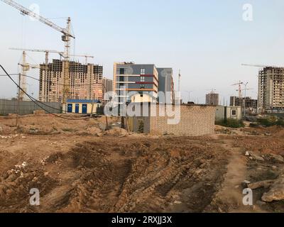 Schmutz auf einer Baustelle. Furchen anschleifen, Spuren von schweren Fahrzeugen. Es gibt Häuser in der Nähe, einen Stand mit Transformatoren. Baulandschaft. Stockfoto