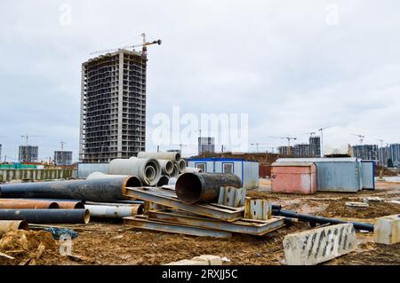 Große Abwasserrohre aus schwarzem Kunststoff und Beton aus Zementzement für den Bau von Wasserrohren oder Abwasserkanälen auf einer Baustelle während des Vertriebs Stockfoto