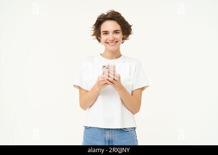 Porträt einer brünetten Frau mit Smartphone, stehend mit Handy, SMS, Bestellung aufgeben, soziale Medien am Telefon durchstöbern, stehen Stockfoto