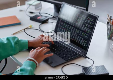 Nahaufnahme einer Frau, die während der Arbeit am Arbeitsplatz Codes auf dem Laptop eingibt Stockfoto