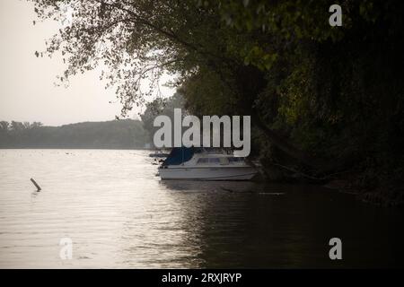 Ein Motorboot legte am frühen Morgen am Flussufer an Stockfoto