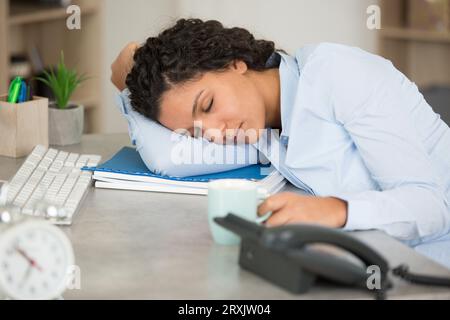 Schöne Frau, die auf ihrem Schreibtisch im Besprechungszimmer schläft Stockfoto