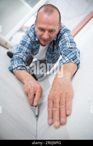 Männlicher Teppichmonteur, der Teppich mit Cutter installiert Stockfoto