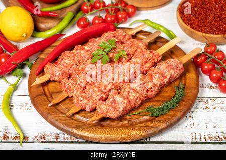 Adana Kebab auf Holzgrund. Roher Shish adana Kebab mit Kräutern und Gewürzen Stockfoto