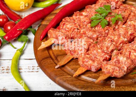 Adana Kebab auf Holzgrund. Roher Shish adana Kebab mit Kräutern und Gewürzen. Leerzeichen kopieren. Freier Speicherplatz für Text Stockfoto