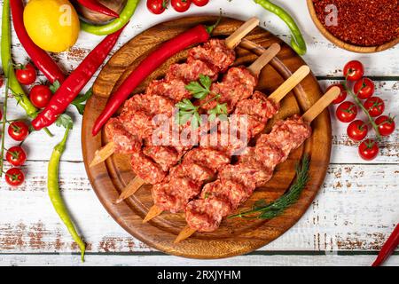 Adana Kebab auf Holzgrund. Roher Shish adana Kebab mit Kräutern und Gewürzen Stockfoto