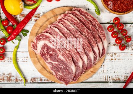 Rohes frisches Fleisch-Ribeye-Steak auf Holzgrund. Rohes Wagyu-Ribeye mit Kräutern und Gewürzen Stockfoto