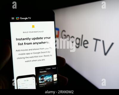 Person, die ein Smartphone mit einer Webseite mit Video-on-Demand-Service Google TV auf dem Bildschirm vor dem Logo hält. Konzentrieren Sie sich auf die Mitte der Telefonanzeige. Stockfoto