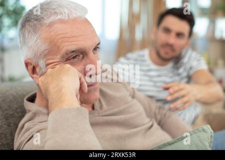 Sohn, der seinen Vater auf einem modernen Sofa beleidigt Stockfoto