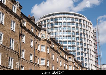 Die brutalistische Fassade von Harry Hyams' Space House in der Kemble Street neben Häusern auf dem Peabody Trust Estate, London, WC2, England, Großbritannien Stockfoto