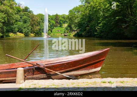 Uman, Ukraine - 24. Juni 2023: Blick auf den Schlangenbrunnen im Sofievsky Arboretum im Sommer, Uman. Holzboot am Pier auf dem See. Stockfoto