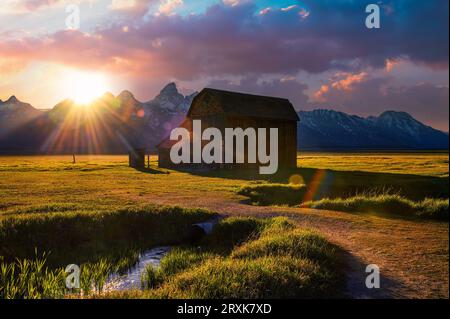 Sonnenuntergang über einer historischen Scheune in der Mormon Row im Grand Teton National Park, Wyoming Stockfoto