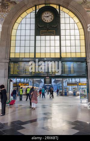 Hauptbahnhof mit Fahrplan, Uhr und Touristen. Halle des berühmten Bahnhofs Sao Bento. Das Innere des alten Bahnhofs in Porto. Stockfoto