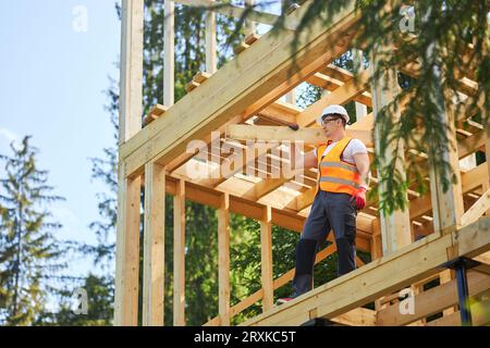 Starker männlicher Baumeister, hält, hebt, trägt Holzbrett, gilder, wir freuen uns auf Sie. Stockfoto