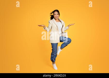 Fröhliche junge asiatische Frau im Jackenspringen, friert in der Luft, hat Spaß, genießt gute Stimmung, Freizeit Stockfoto