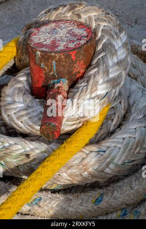 Schwere Seile, die um einen Schiffspoller an einem Hafen am Hafen gewickelt sind. Stockfoto