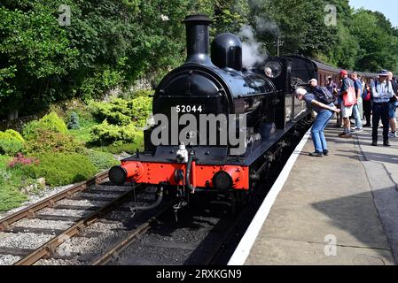 Die Passagiere sammeln sich um die L&Y-Klasse 25 0-6-0 2F-Lokomotive Nr. 52044 am Bahnhof Oxenhope der Keighley & Worth Valley Railway. Stockfoto