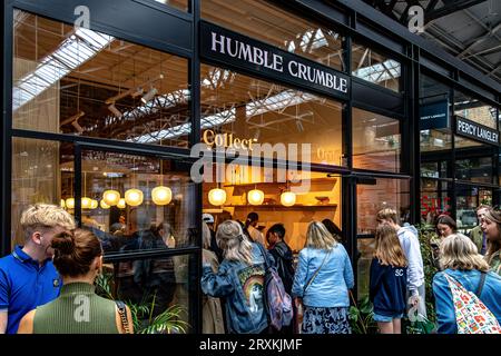 Leute, die Schlange stehen, um in das beliebte Dessertrestaurant Humble Crumble am Old Spitalfileds Market, London E1, zu kommen Stockfoto