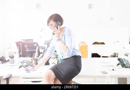 Geschäftsfrau mit Brille Gespräch am Telefon im Büro Stockfoto