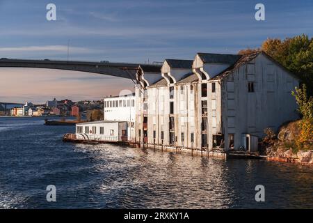 Blick auf die norwegische Küstenlandschaft mit alten Holzscheunen und einer Brücke im Hintergrund. Eingang zur Kristiansund-Bucht Stockfoto