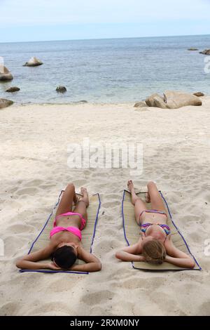 Junge Frauen am Strand Sonnenbaden Stockfoto