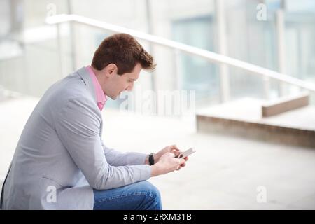 Mitte der erwachsene Mann mit Smart Phone auf Treppe Stockfoto