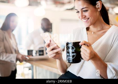 Geschäftsfrau mit Kaffeetasse und Smartphone Stockfoto