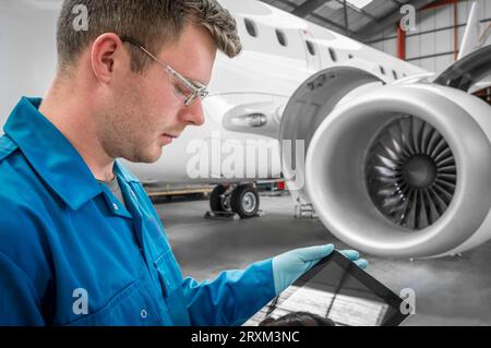 Junger Mann, der ein digitales Tablet im Flugzeug benutzt Stockfoto
