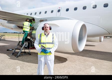 Ein Mann mittleren Alters, der ein digitales Tablet im Flugzeug hält Stockfoto