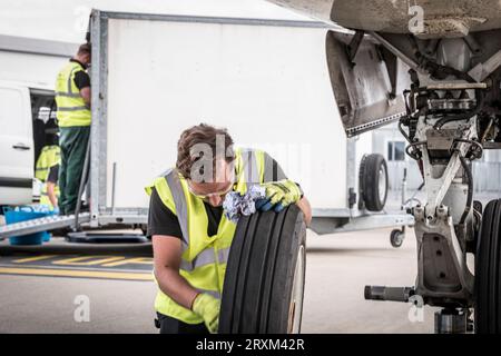 Ein Mann, der am Flugzeugrad arbeitet Stockfoto