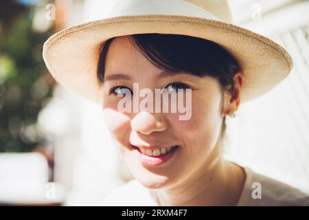 Lächelnde junge Frau mit Strohhut Stockfoto