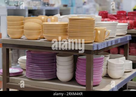 Geschirr wird im Laden verkauft. Reihen von verschiedenen gelben Schüsseln und Tellern für zu Hause in Regalen in einem Geschäft. Stockfoto