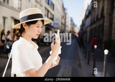 Junge Frau fotografiert mit Smartphone auf der Straße Stockfoto