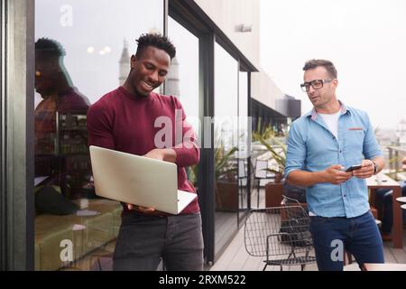 Unternehmer mit Laptop auf dem Balkon Stockfoto