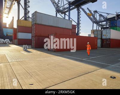 Hafenarbeiter durch Stapel von Cargo Container im Hafen von Felixstowe, England Stockfoto