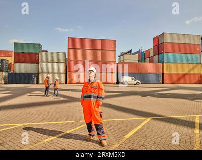 Hafenarbeiter in reflektierenden Overalls von Frachtcontainern Stockfoto