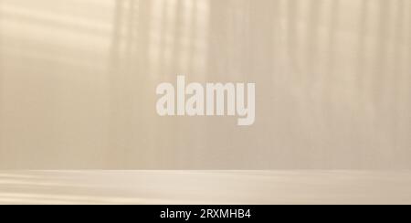 Minimalistischer abstrakter, sanfter, hellbeiger Hintergrund für die Produktpräsentation mit hellem und aufwändigem Schatten vom Fenster und Vegetation an der Wand Stockfoto