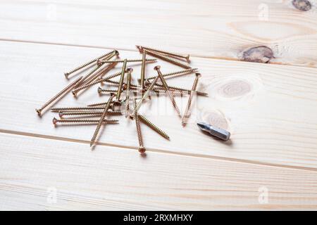 Stapel Schrauben und Schraubendreherbit auf einem Holztisch. Blechschraube für Holz Stockfoto