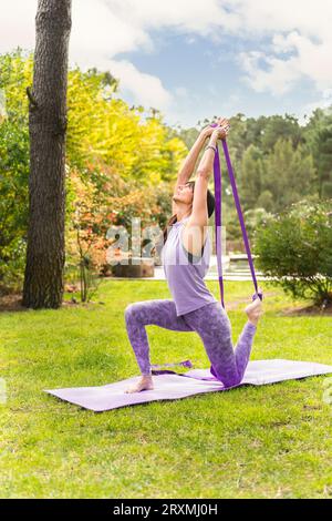 Mittelgroße Erwachsene Frau, die Yoga mit Gurt ausübt. Stockfoto