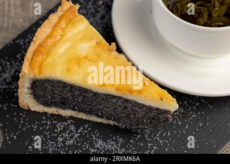 Ein geschnittenes Stück Kuchen mit Mohnsamen Füllung, eine dicke Schicht Mohnsamen, die sich zwischen dünnen Schichten von Schwammkuchen im Dessert füllt Stockfoto