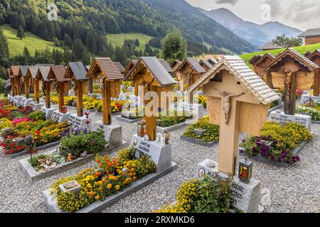 Auf dem Friedhof hinter der Kirche St. Stephan in Jaun haben alle einzelnen Gräber ein geschnitztes Holzkreuz mit einer Figur Christi und Schnitzereien, die den Beruf oder das Hobby des Verstorbenen darstellen. Jaun, Schweiz Stockfoto