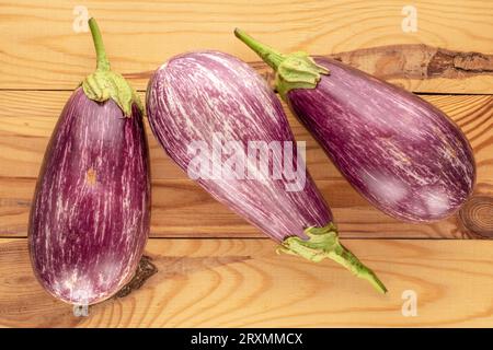 Drei reife Auberginen auf einem Holztisch, Makro, Draufsicht. Stockfoto